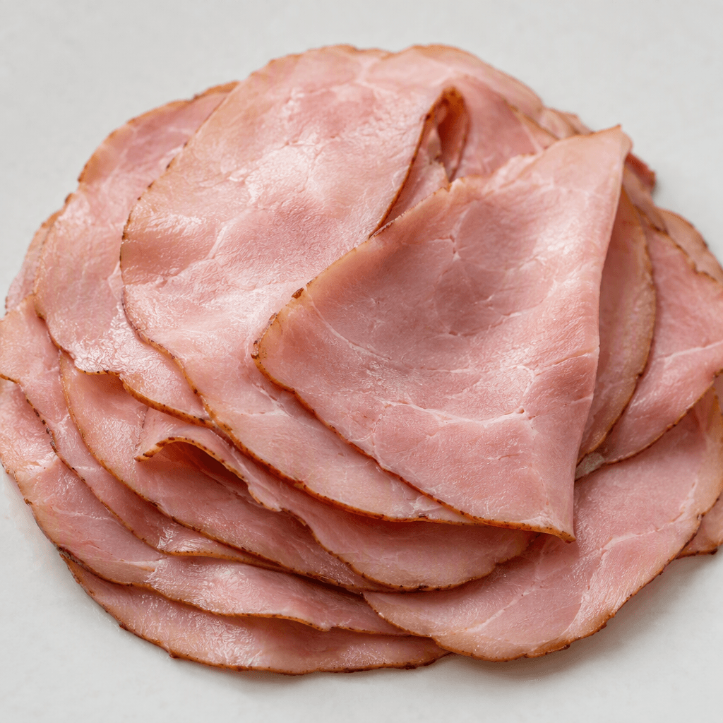 Thin, overlapping slices of rosy-pink smoked deli meat have a smooth, slightly moist surface and a narrow darker edge.