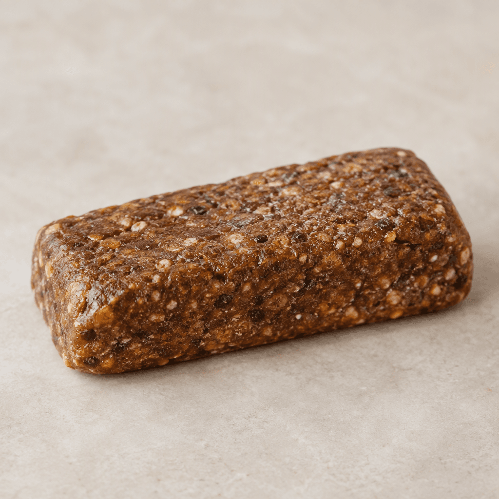 A compact, rectangular protein bar with a dense, slightly rough brown surface and softly rounded edges.