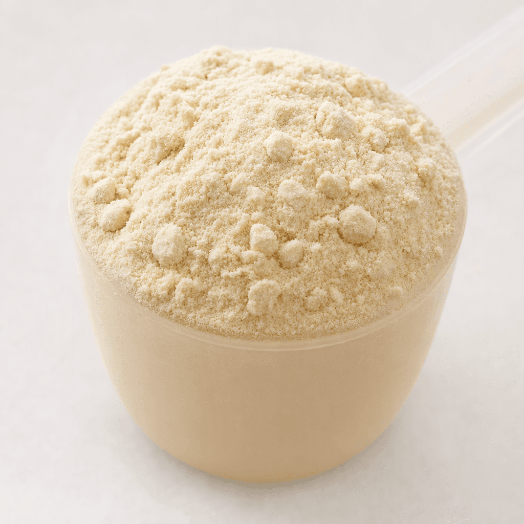 Yüzeyi hafifçe tepecik oluşturan, birkaç küçük topaklı, ince dokulu açık bej protein tozu tek ölçek hâlinde görülüyor.