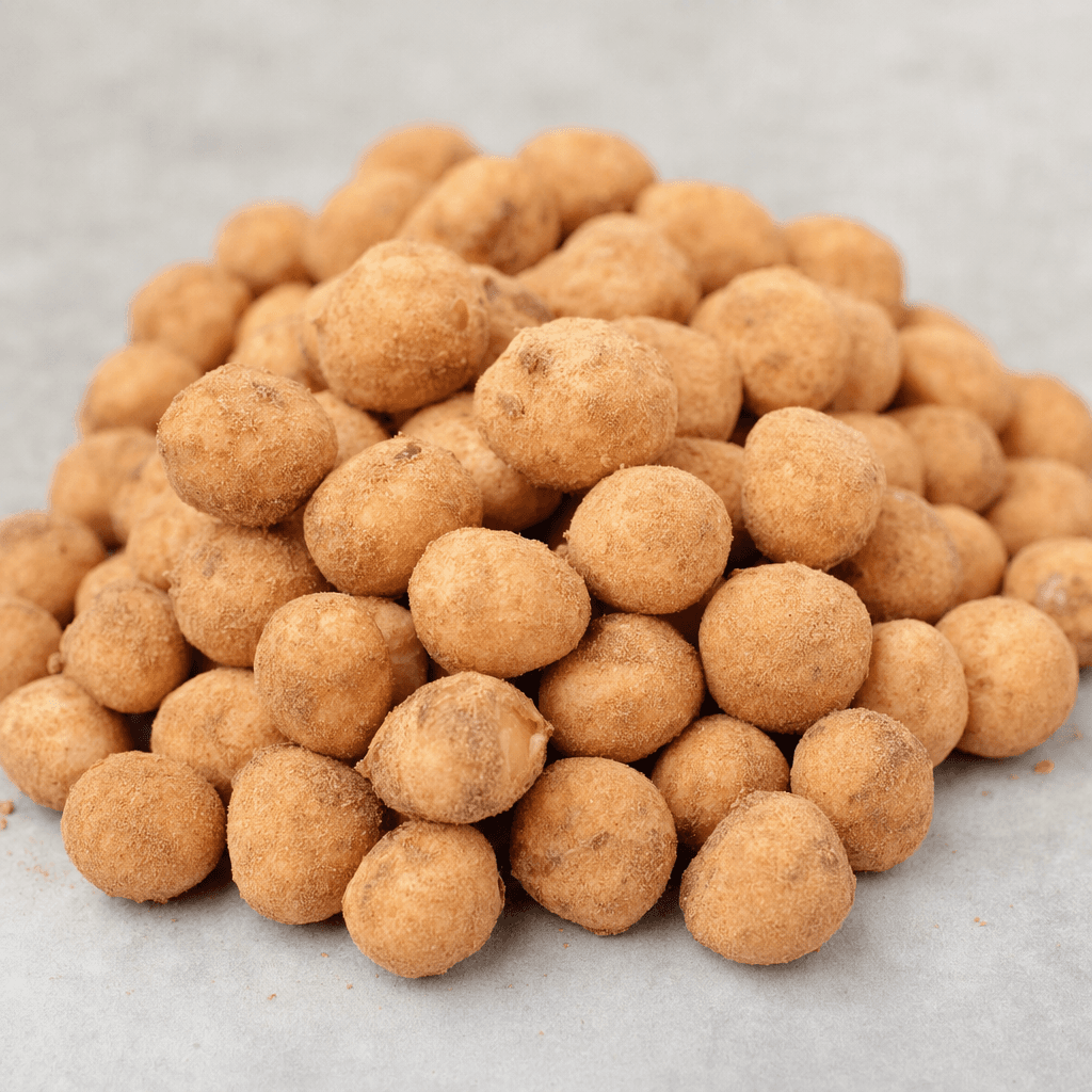 Small rounded hazelnuts are covered in a thin, matte beige-brown coating with a slightly grainy surface and are served loose in a small pile.