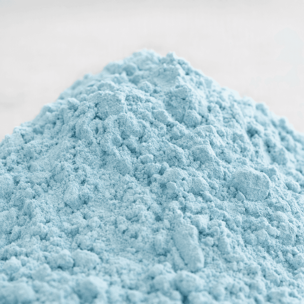 Yumuşak, hafif topaklı dokusuyla küçük bir yığın hâlinde duran açık mavi protein tozu.