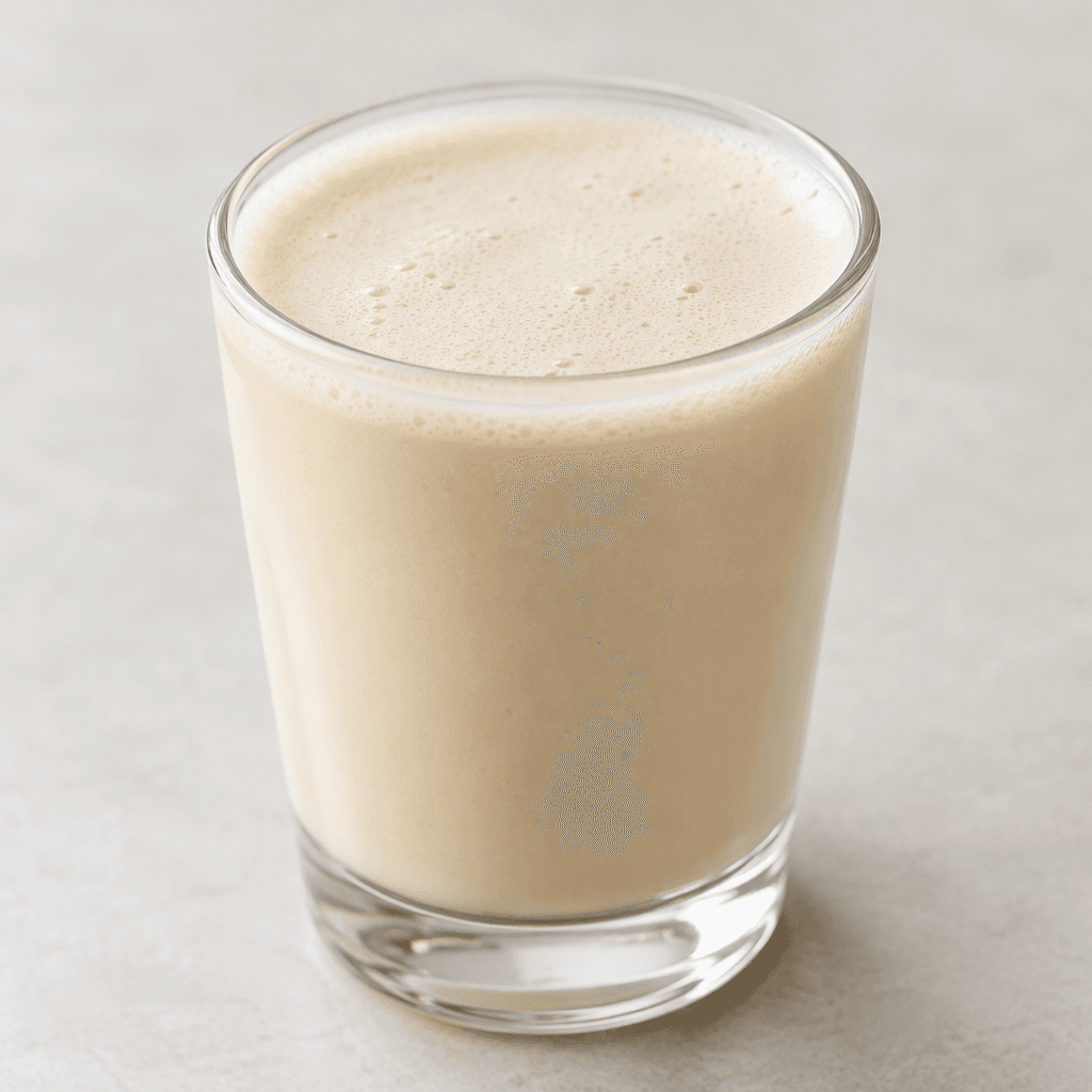 An opaque, pale beige drink with a smooth, slightly foamy surface, served in a clear glass.