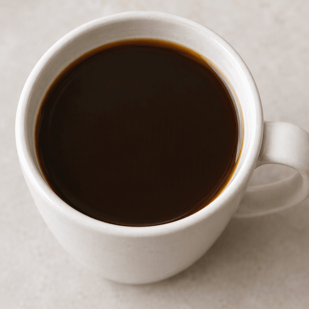 A cup of smooth, opaque dark-brown coffee with a plain, unadorned surface.