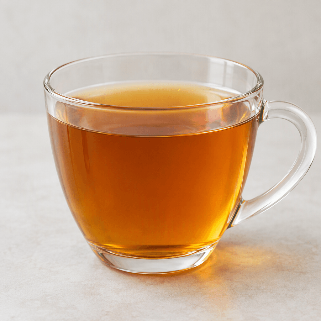 A clear, warm amber-colored tea is served in a transparent glass, with no visible garnish.