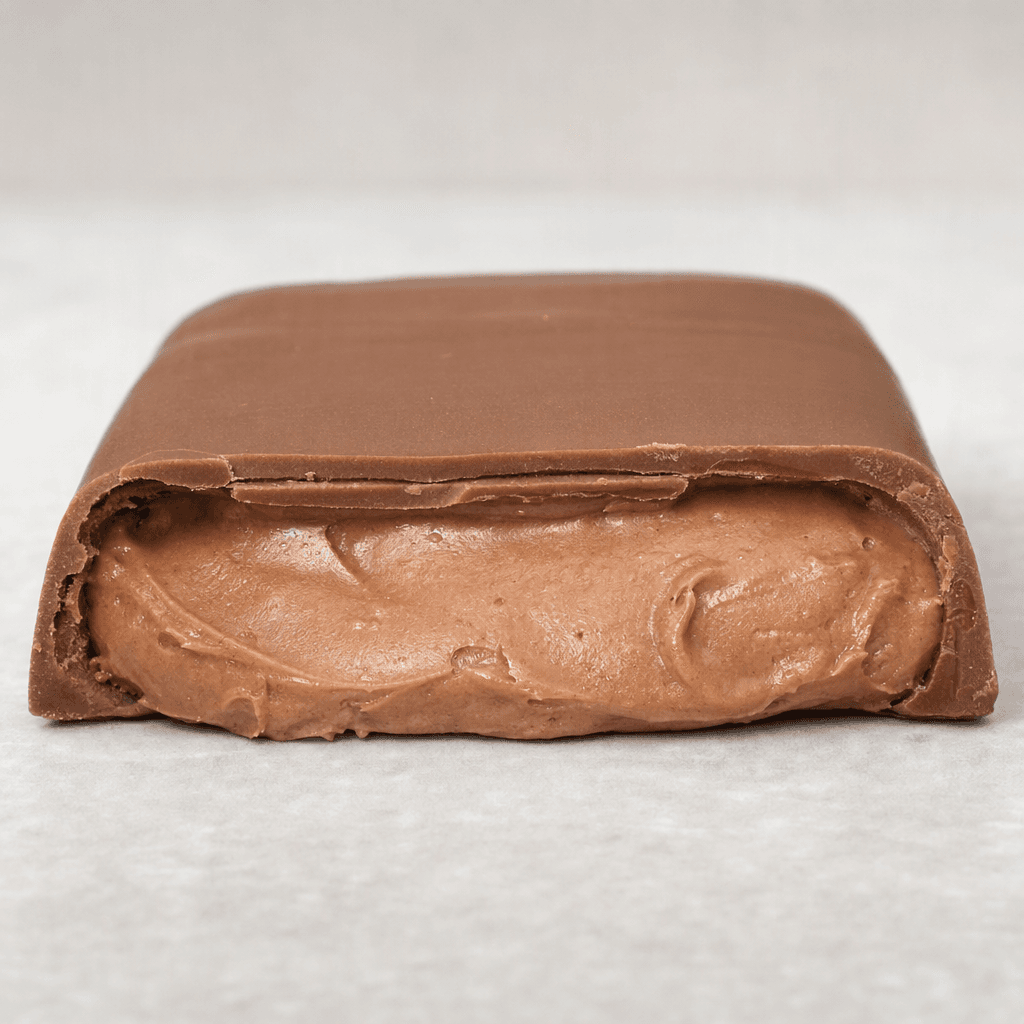 A rectangular milk-chocolate bar with a smooth brown shell and a thick, pale-brown hazelnut spread filling visible where it is cut.