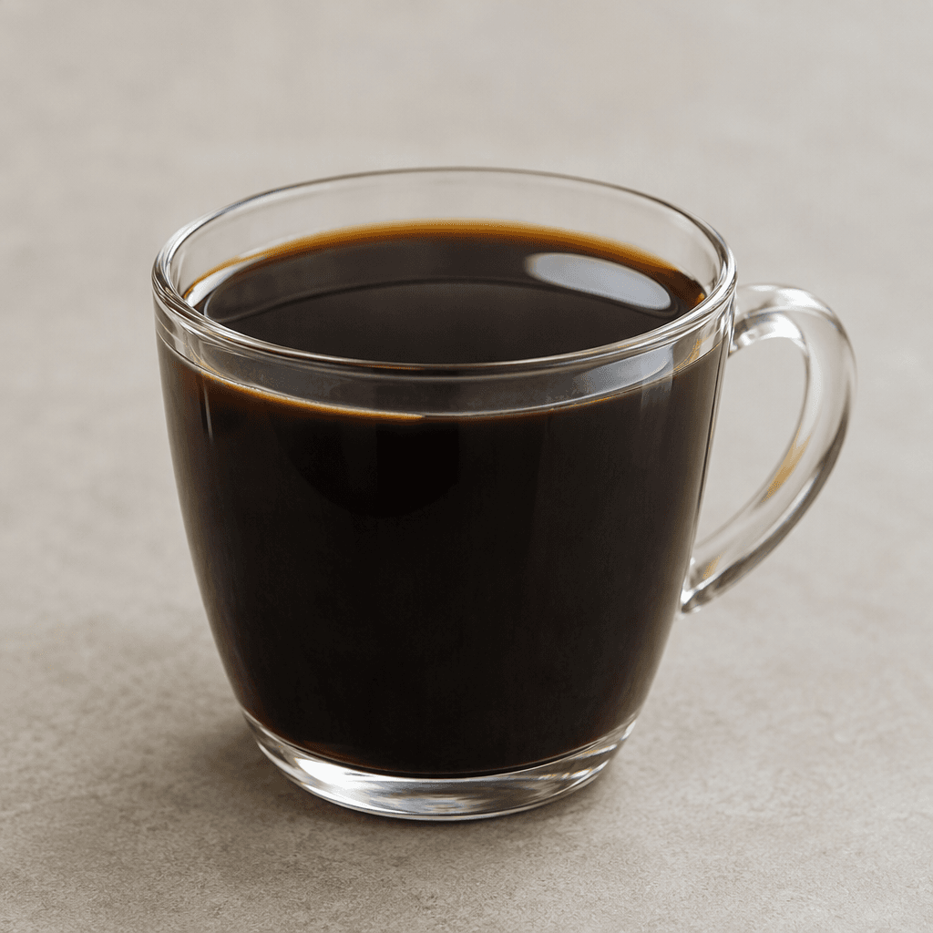 A clear glass cup filled with opaque, nearly black liquid, its smooth surface reflecting a small highlight, with no milk, foam, or visible solids.