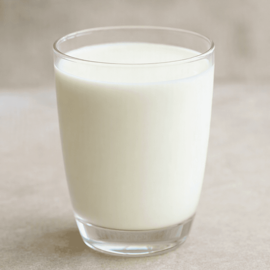 A smooth, opaque, pale-white milk drink fills a clear glass.