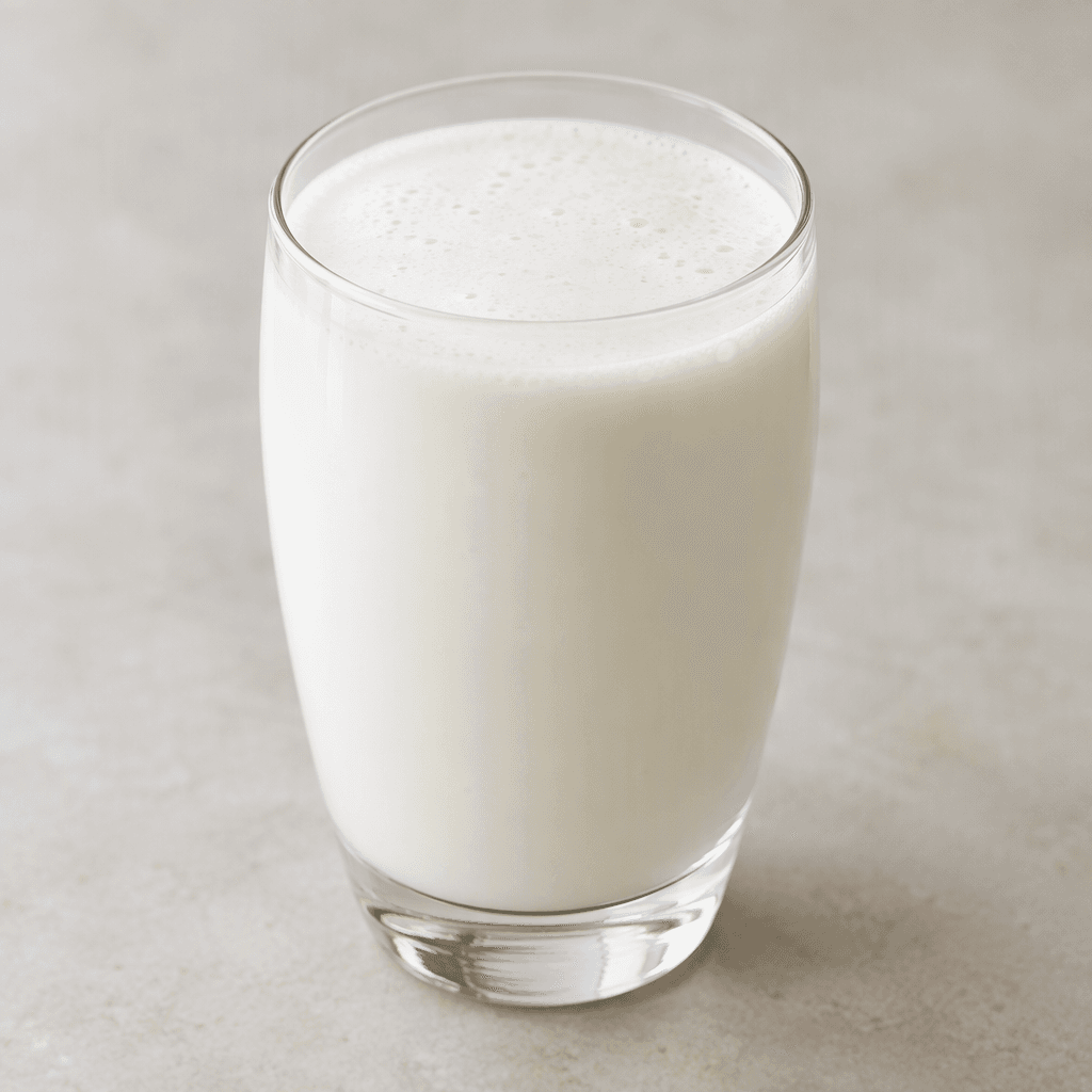 An opaque, milky-white, pourable yogurt drink with a smooth, lightly frothy surface, served in a clear glass.