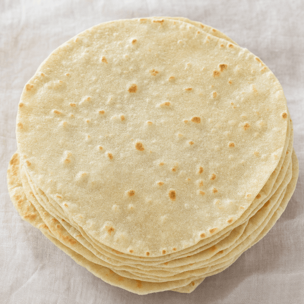 A stack of round, thin, pale beige flatbreads with softly browned spots, a matte surface and slightly uneven edges.