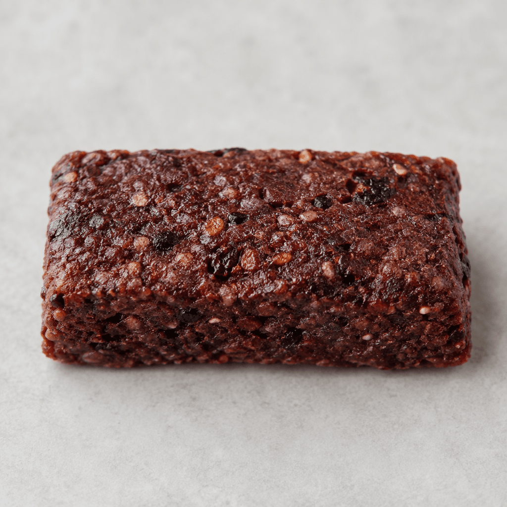 A compact rectangular snack bar with a deep reddish-burgundy, slightly uneven surface and small darker flecks throughout.