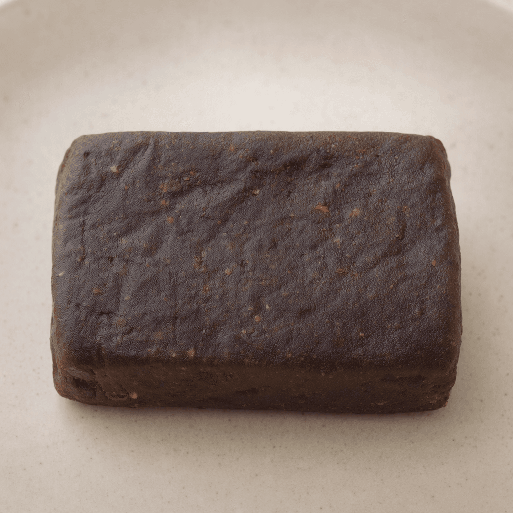 A compact, rectangular dark-brown bar with rounded corners and a slightly uneven, matte surface.