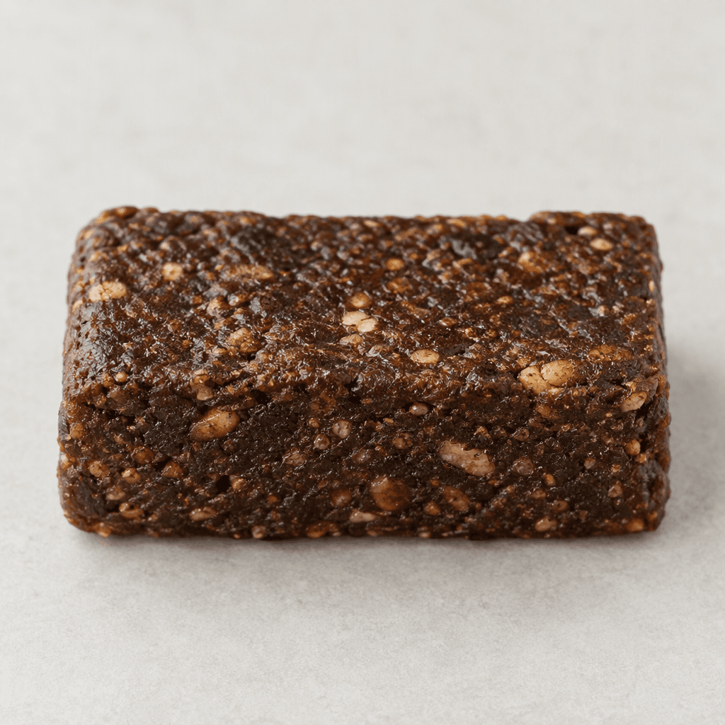 A compact, rectangular dark-brown bar with a dense, slightly uneven surface and a few lighter brown flecks.