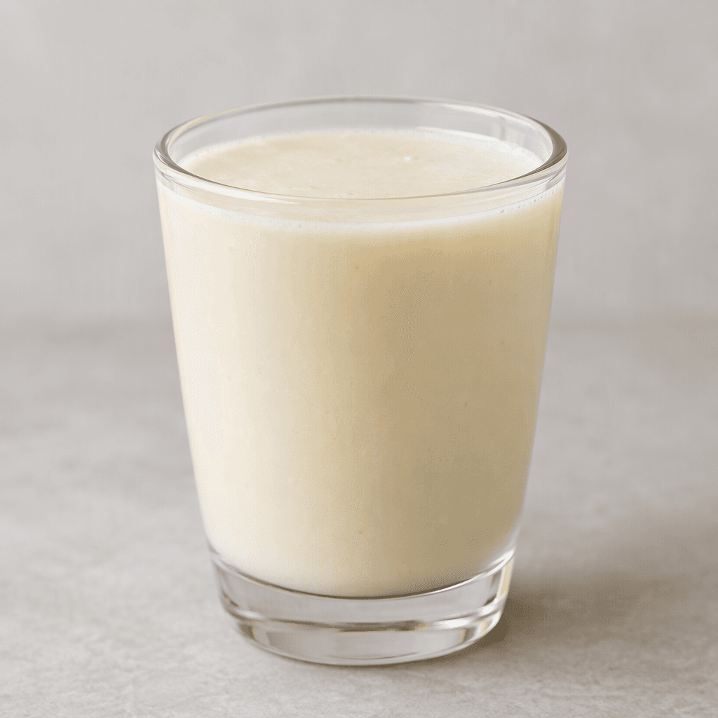 A small glass holds an opaque, smooth, pale ivory drink with a slightly creamy appearance.